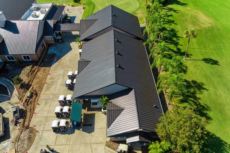 Representative aerial view of a Southwest Florida golf clubhouse with a dark standing-seam metal roof