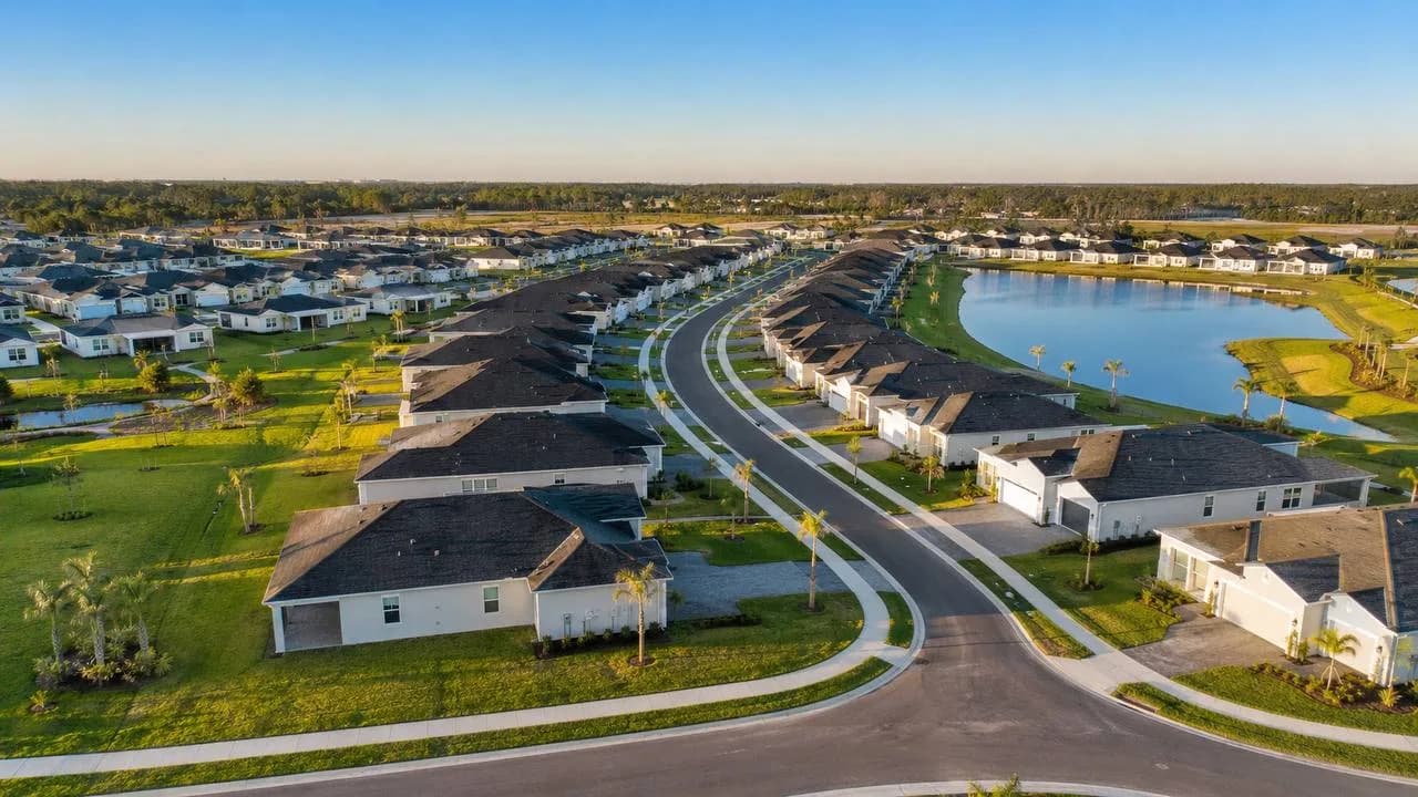 Aerial view of a newly completed single-family build-to-rent community in Southwest Florida, with rows of new homes, curving streets, and a retention lake