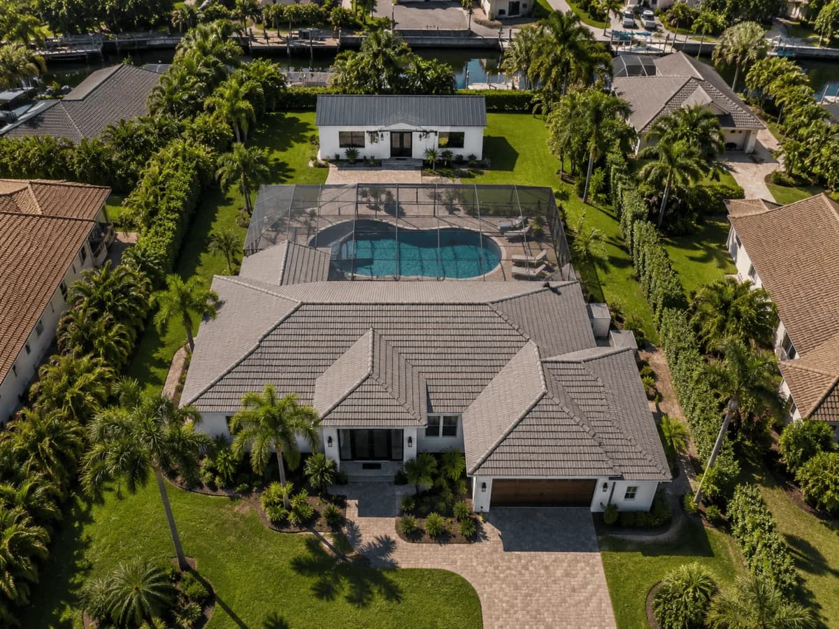 Aerial view of container guest house installed behind main house with connected patio and pool area in a Southwest Florida suburban neighborhood