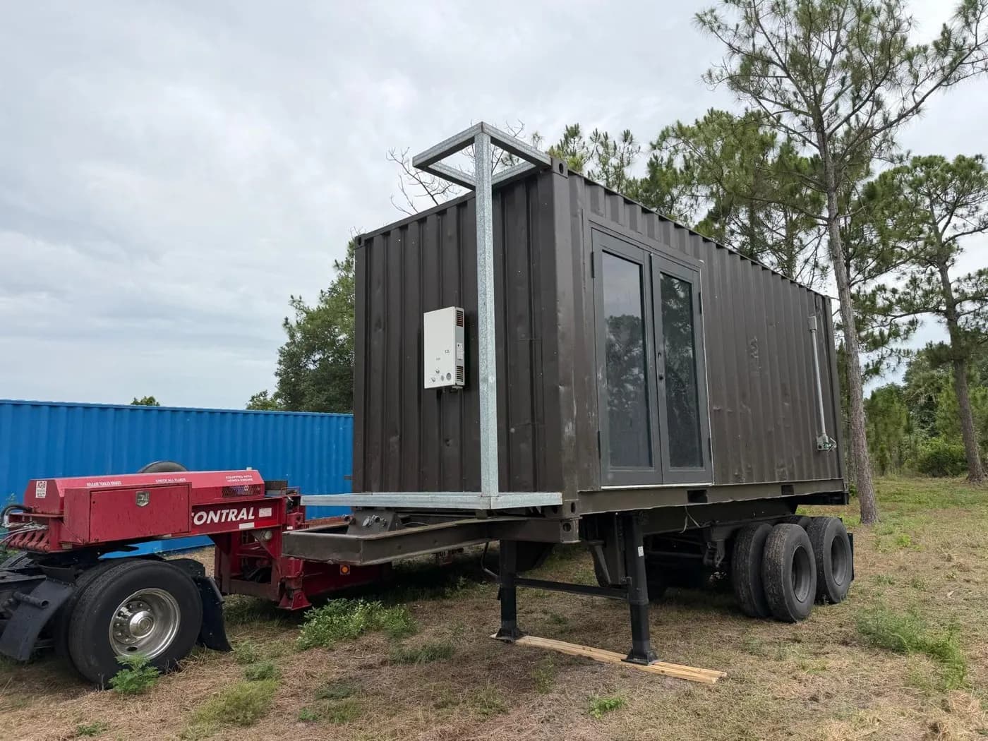 Three-quarter exterior view of the actual 20-foot mobile container with glass doors and rooftop steel frame