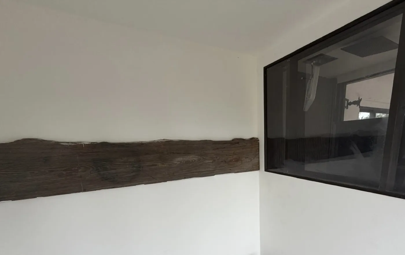 Interior accent wall with a horizontal reclaimed-wood band and an interior pass-through window framed in black