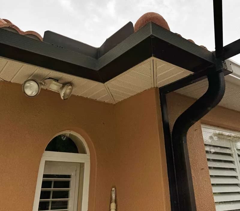 Representative view of dark aluminum gutters, fascia, and soffits on a tile-roof Florida home