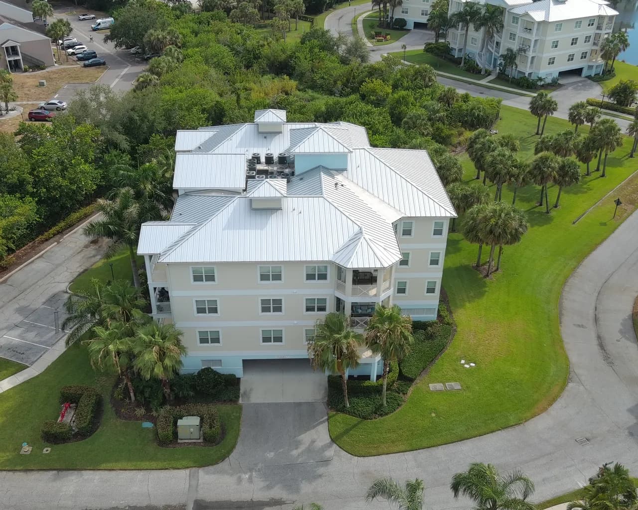 Daylight drone view of a multi-story Florida building with a standing-seam metal roof